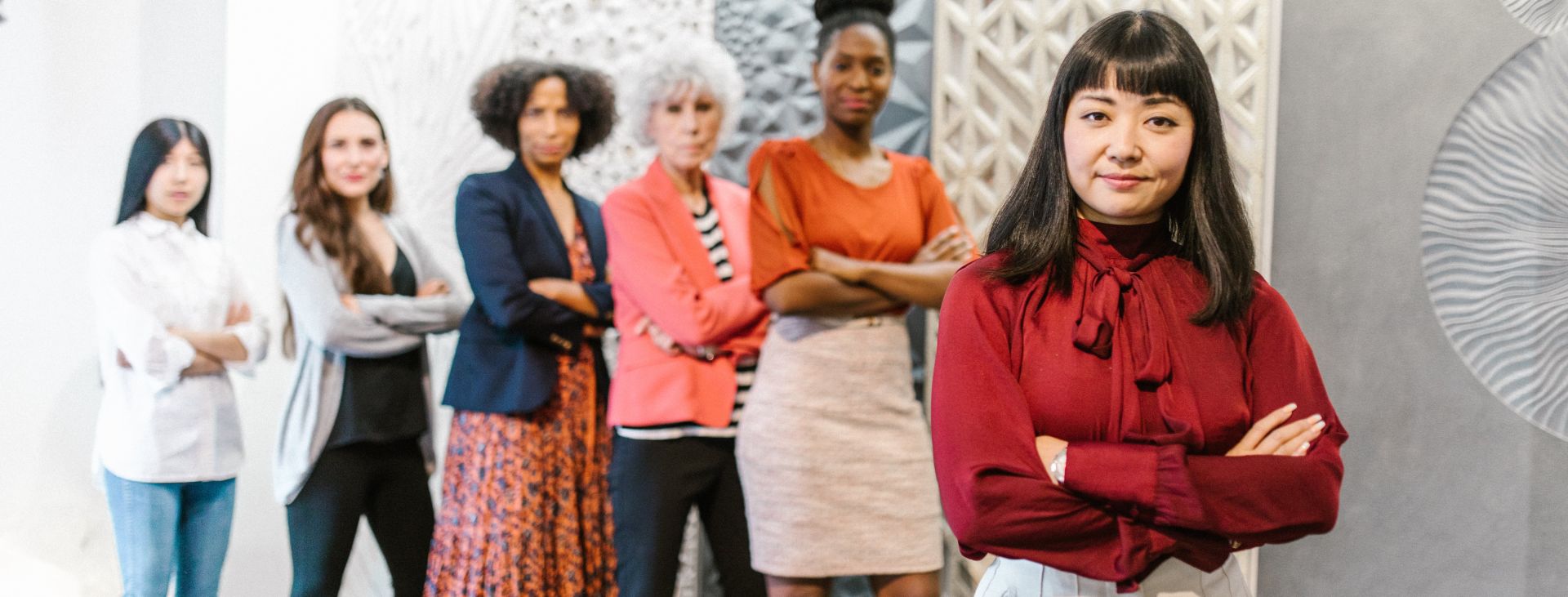 A Woman in Red Long Sleeves Standing with Her Arms Crossed with People Standing Behind Her