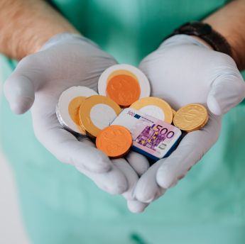 Faceless doctor with chocolate coins in hands